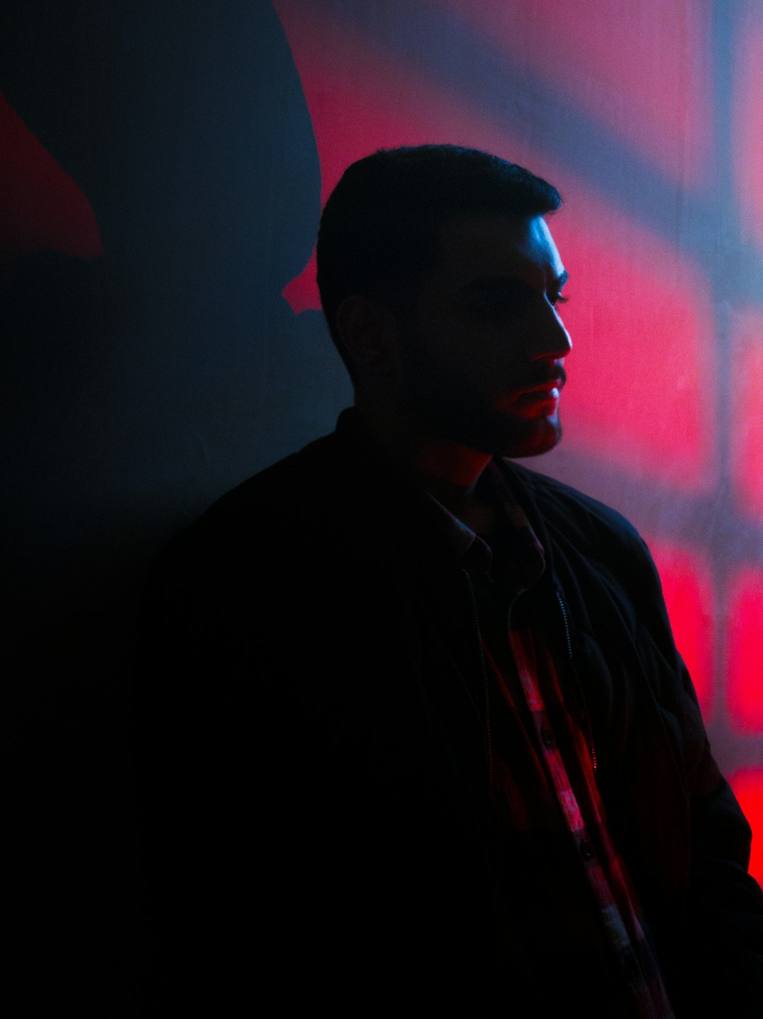 Man silhouetted against red graffiti wall